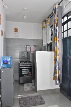A compact kitchen with a gas stove, oven, and a water dispenser. - AJ Urban Escape (Nairobi)