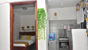 A compact room with a bed, a water dispenser, a stove, and a hanging plant. - AJ Urban Escape (Nairobi)
