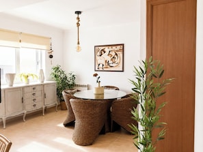A dining area with wicker furniture, a round table, and a hanging light fixture.