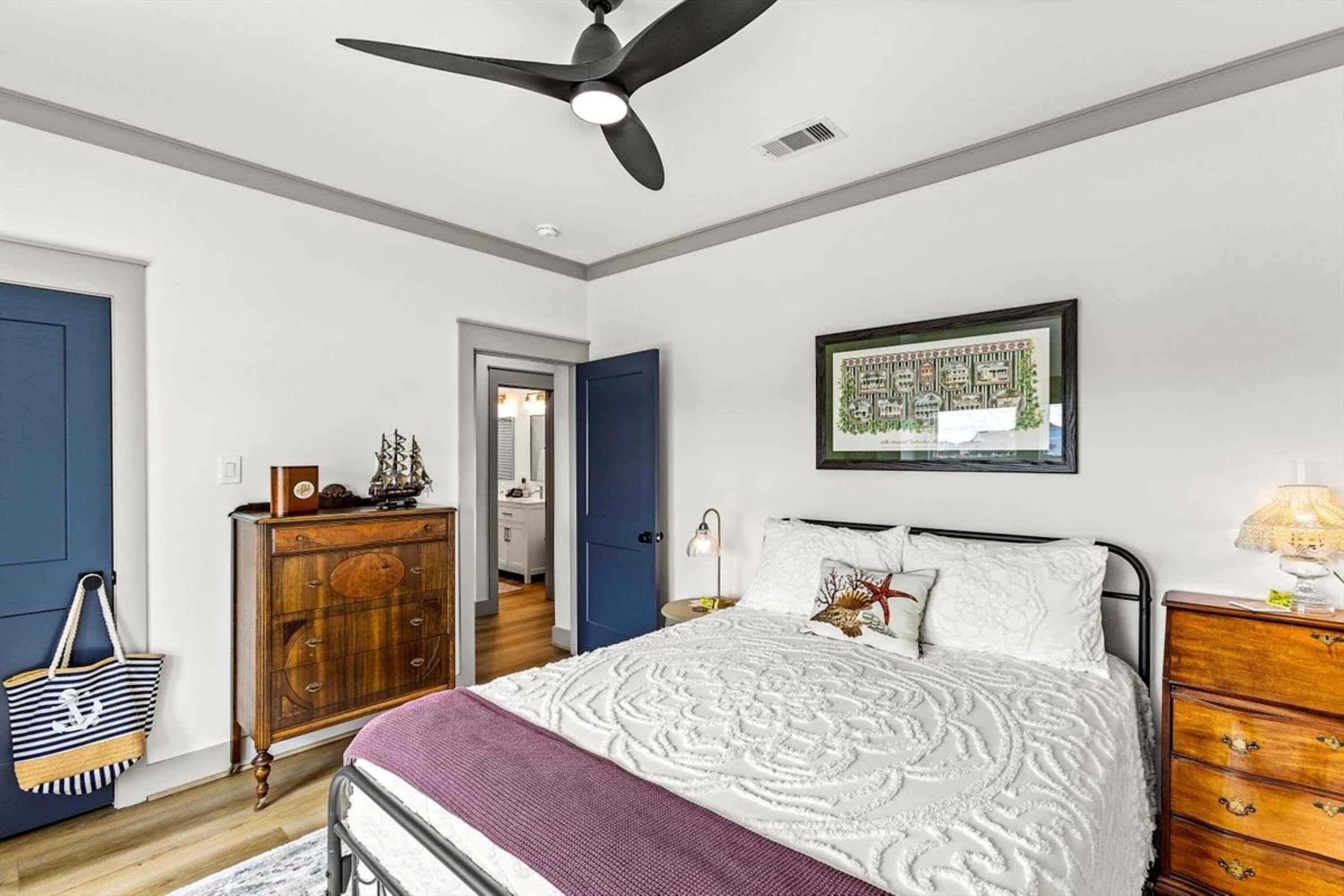 Een slaapkamer met een bed, een dressoir, een plafondventilator en een lijst met een kaart aan de muur.