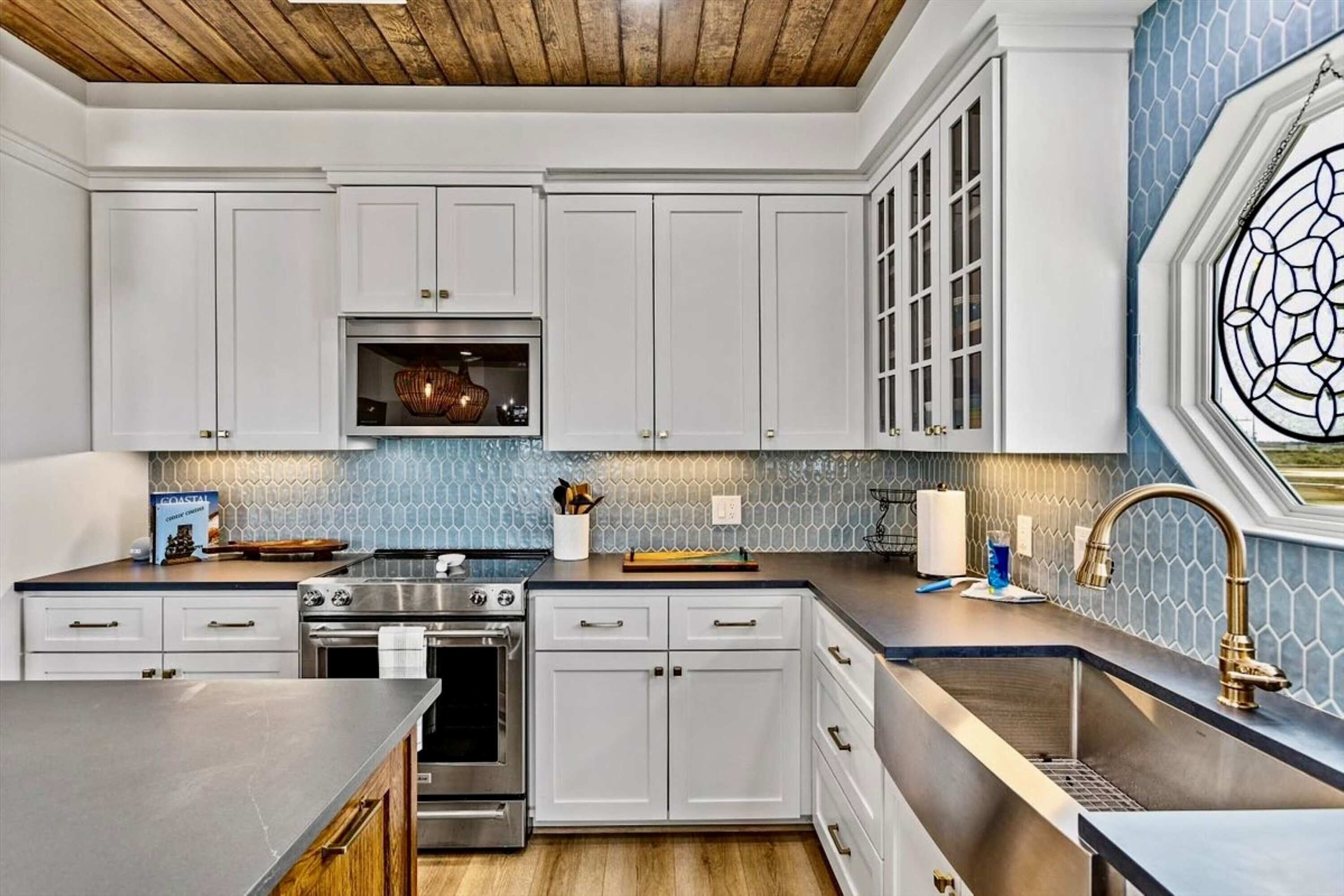 A modern kitchen with white cabinets, stainless steel appliances, and a blue-tiled backsplash.