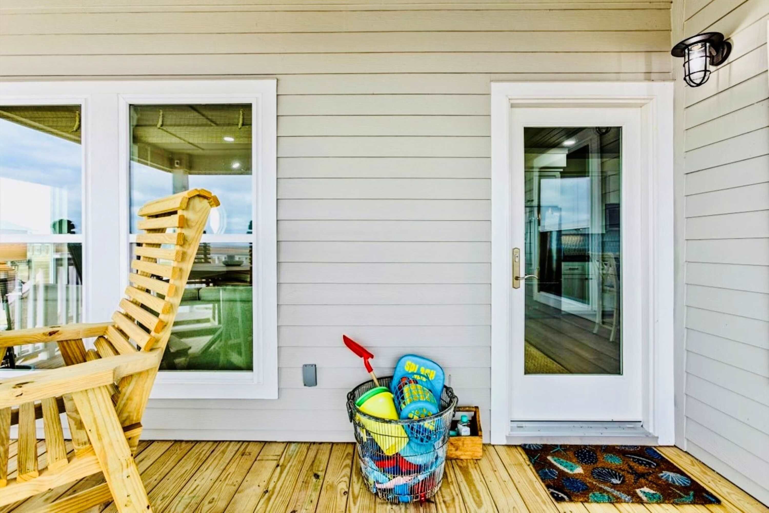 A wooden deck with a rocking chair, a glass door, and a basket with items.