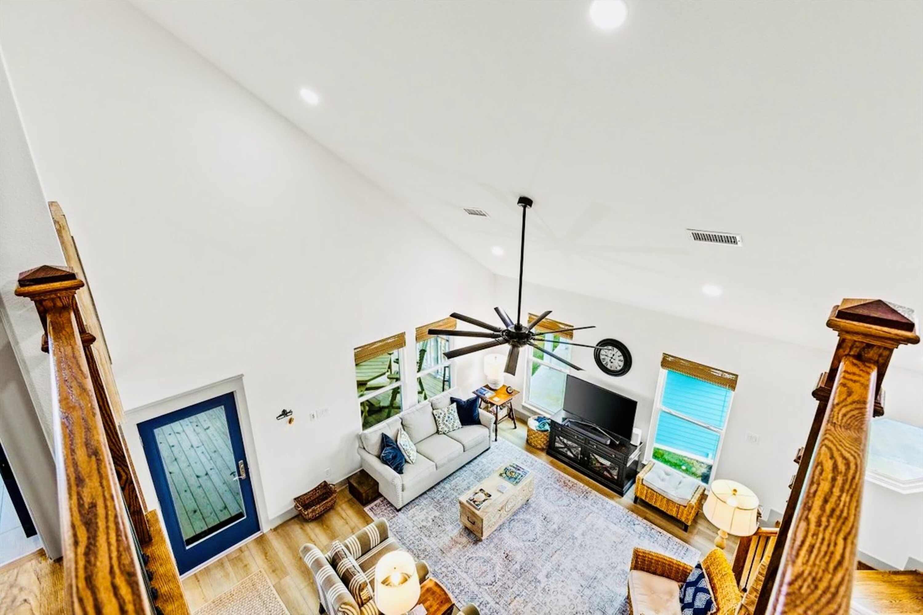 A spacious living area with a ceiling fan, a sofa, a television, and a large window.