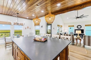 A spacious kitchen with a large island, wooden ceiling, and pendant lighting. - Spoonbill at West Bay (Galveston)
