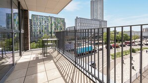 Ein Balkon mit Blick auf eine Stadtlandschaft, darunter Hochhäuser und ein Parkplatz.