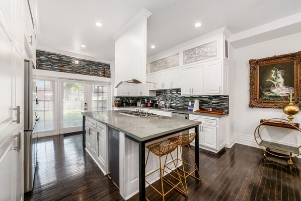 A modern kitchen with a central island, white cabinetry, and a decorative painting.