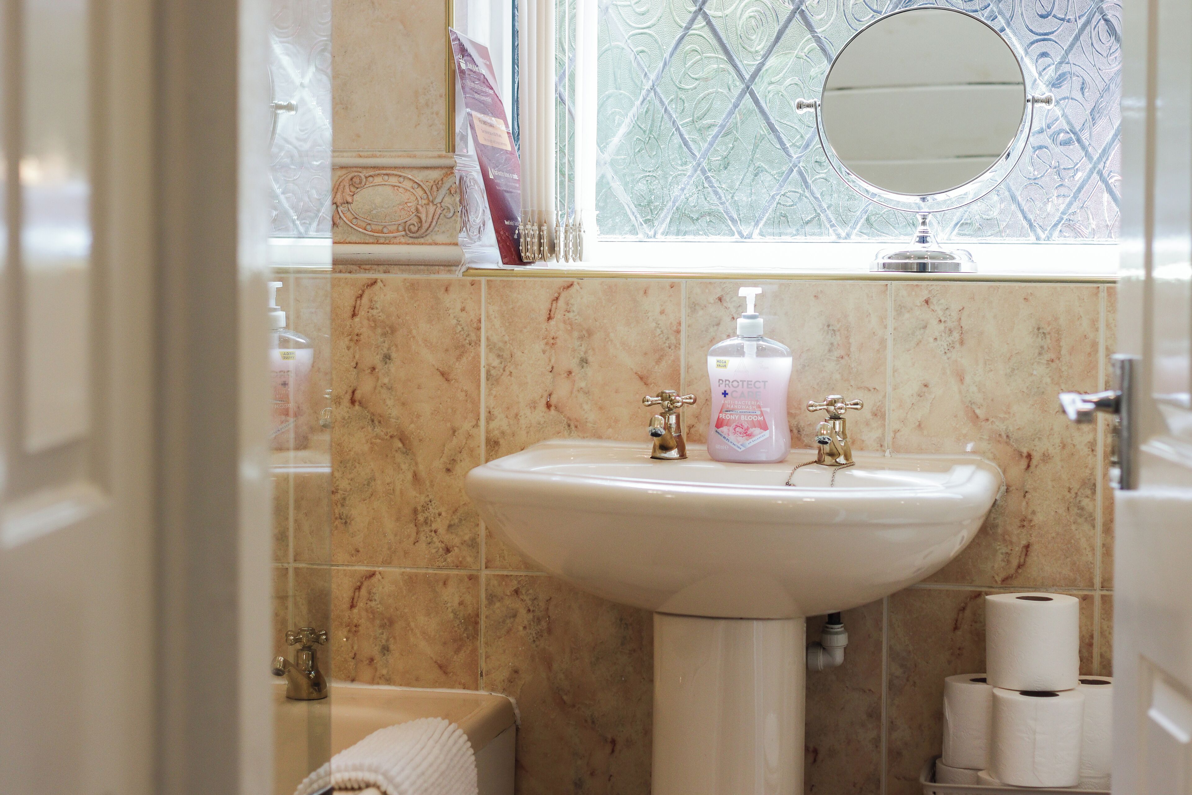 A bathroom with a sink, mirror, and toilet paper.
