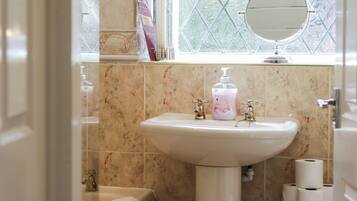 A bathroom with a sink, mirror, and toilet paper.