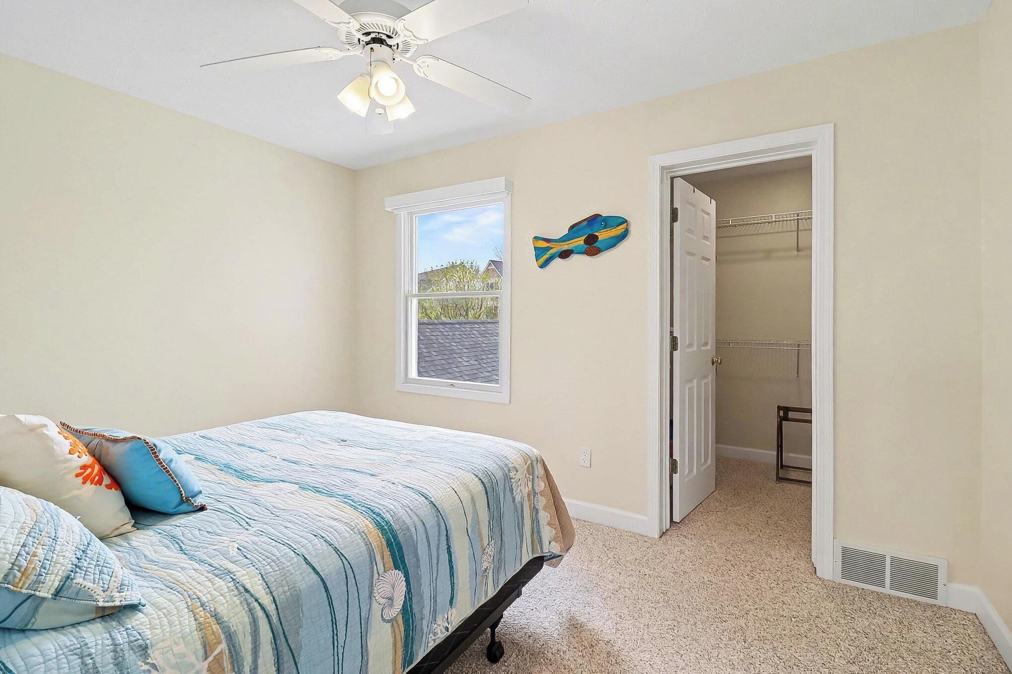 A bedroom with a bed, a ceiling fan, a window, and a closet.