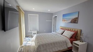 A bedroom with a bed, bedside table, TV, and a painting on the wall. - Dockside Den,  Waterside 3BR, Close to All (Atlantic City)