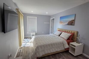 Ein Schlafzimmer mit Bett, Nachttisch, Fernseher und einem Bild an der Wand.