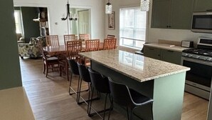 A kitchen with a central island, bar stools, a microwave, and green cabinets. - Perfect Mackinaw City Location! One block to Downtown, Ferry, or Waterfront (Mackinaw City)
