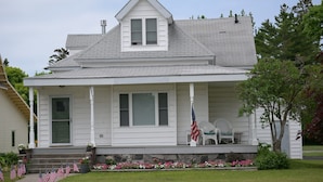 A two-story house with a front porch, a chimney, and a flag. - Perfect Mackinaw City Location! One block to Downtown, Ferry, or Waterfront (Mackinaw City)