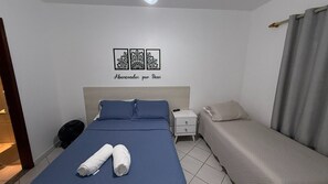 Ein Schlafzimmer mit einem Bett, einem Nachttisch, einer Lampe und einer Wanddekoration.