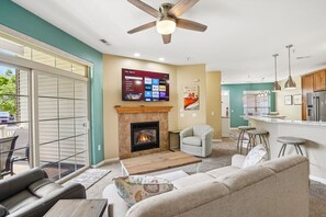 A living room with a fireplace, a TV mounted on the wall, and a ceiling fan. - Whispering Waters at Delton Grand - Ground Floor (Wisconsin Dells)