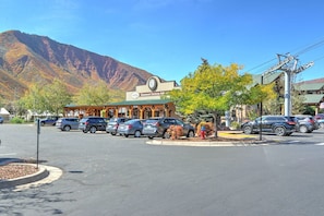 Un parking rempli de voitures, un bâtiment avec une horloge et une montagne en arrière-plan.