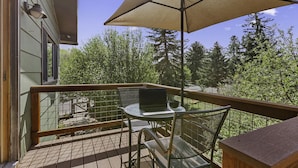 A balcony with a table, chairs, a laptop, and an umbrella. - Charming Studio with Mtn.Views,Walk to Dwntwn (Carbondale)