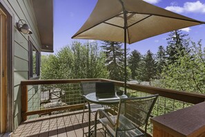 Un balcon avec une table, des chaises, un ordinateur portable et un parasol.