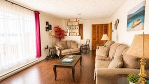 Un salón amplio con suelo de madera, un sofá, una mesa de centro y una lámpara.