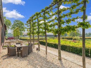 A patio with wicker furniture, a gravel ground, and a view of a cityscape in the background. - Beautiful new Group Home With Panoramic Views (Montfoort)