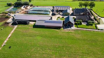 An aerial view of a farm with solar panels, a barn, and open fields.