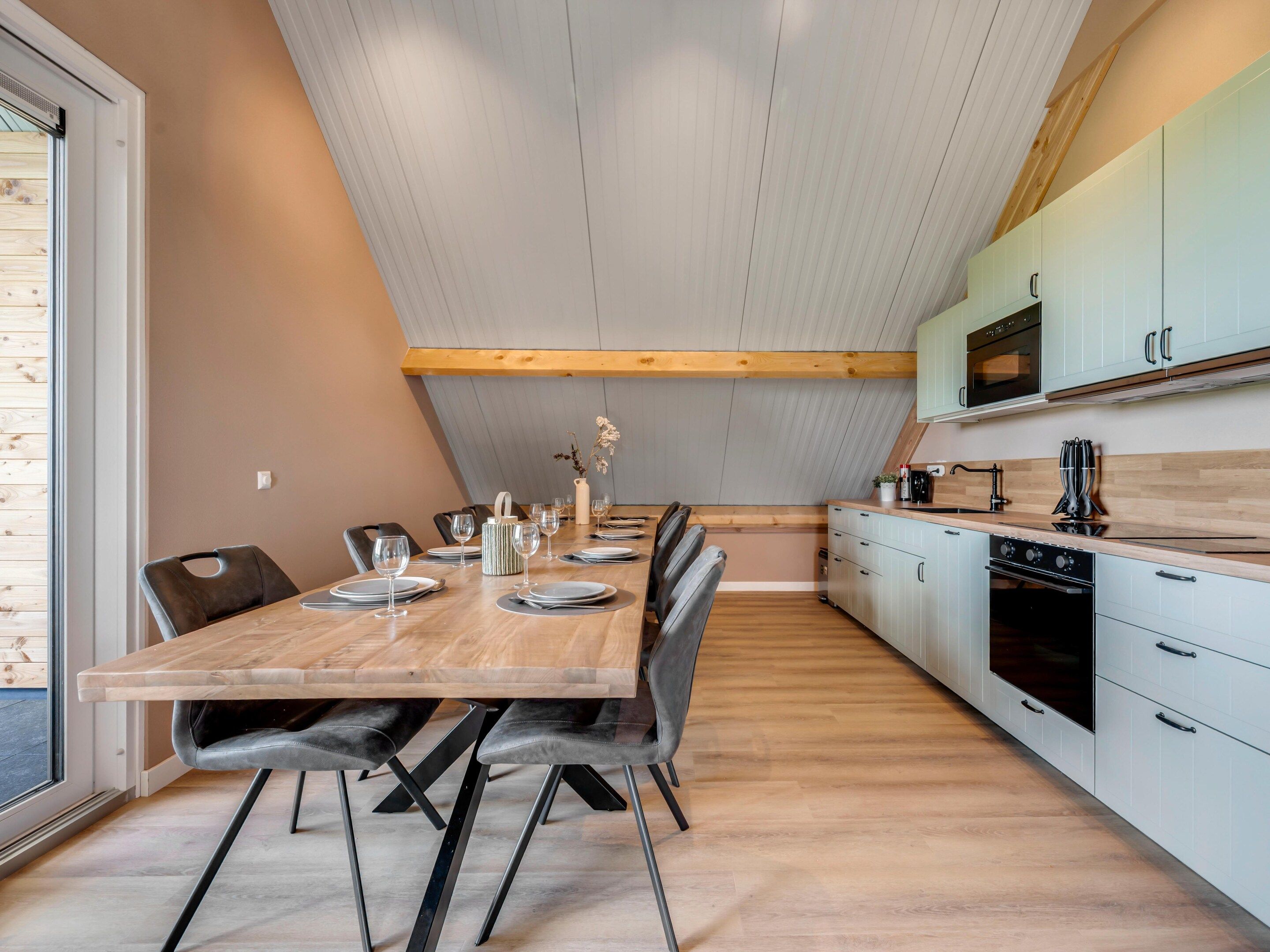 Une cuisine moderne avec un coin repas, comprenant une table en bois, des chaises et un comptoir de cuisine équipé d’appareils électroménagers.