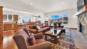 A spacious living area with a fireplace, a large sofa, a coffee table, and a view of the mountains. - 7BR Mountain View Home | Private Hot Tub | Lake & Resort Proximity | Sleeps 16 (Eden)
