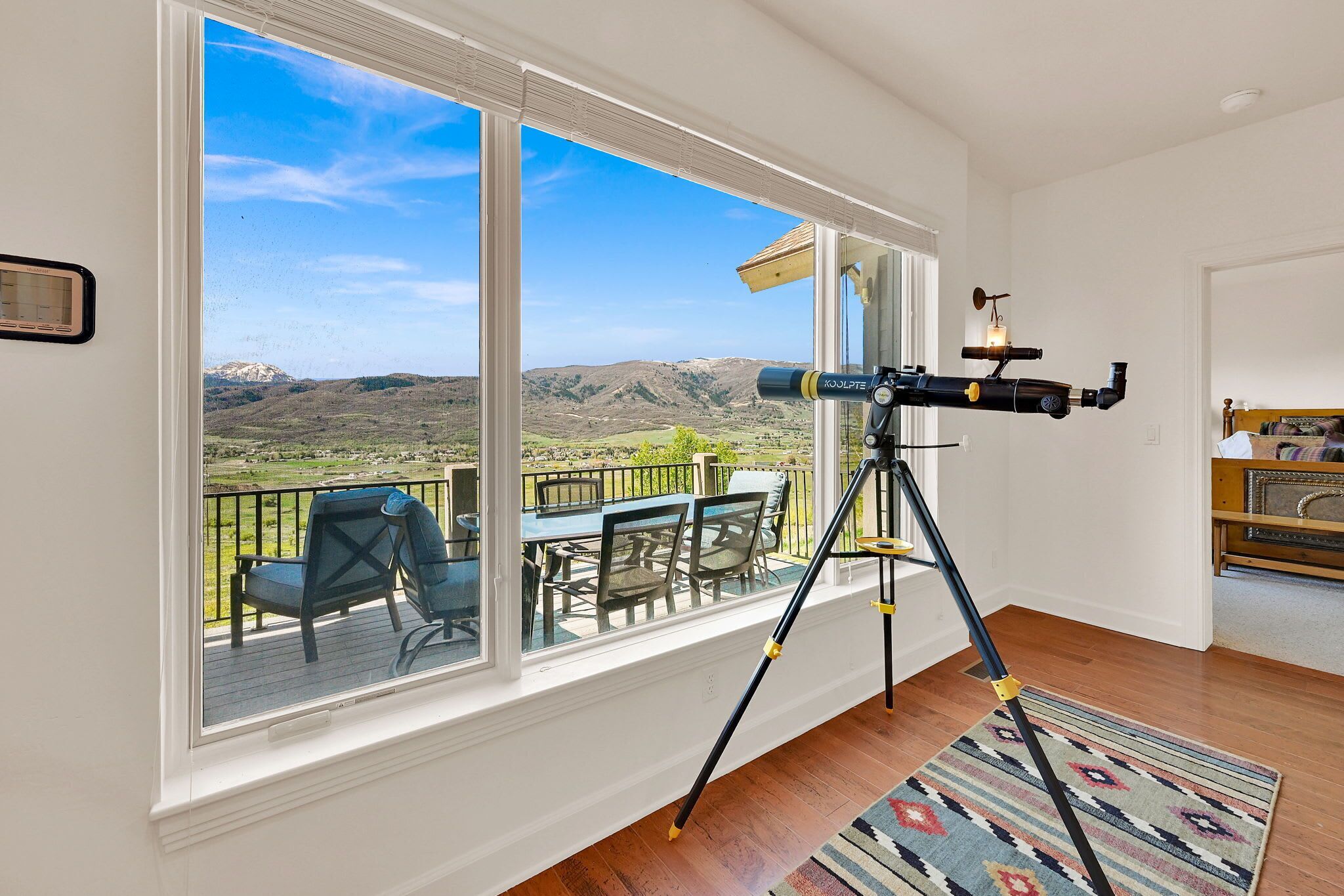 A telescope on a balcony with a view of mountains.