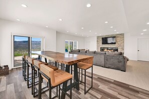 Una cocina moderna con una isla grande, taburetes de bar, una chimenea empotrada y un muro decorativo de piedra.