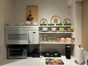 Ett kök med mikrovågsugn, brödrost, vattenkokare och en affisch som föreställer det italienska vinodlingsområdet.