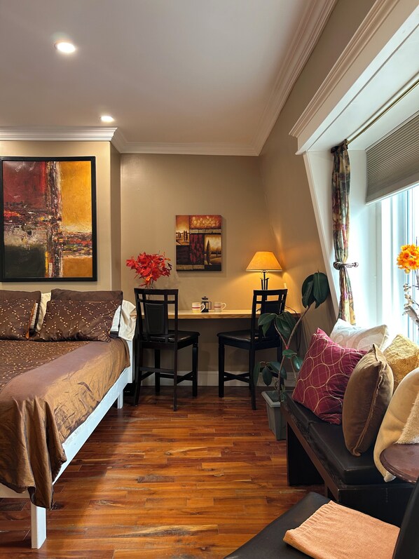 A bedroom with a bed, two chairs, a desk, and a sofa.