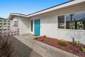 A modern house with a blue door, a white exterior, and a cactus garden. - Mountain View Retreat - Pool, Palms, and Peace (Palm Springs)