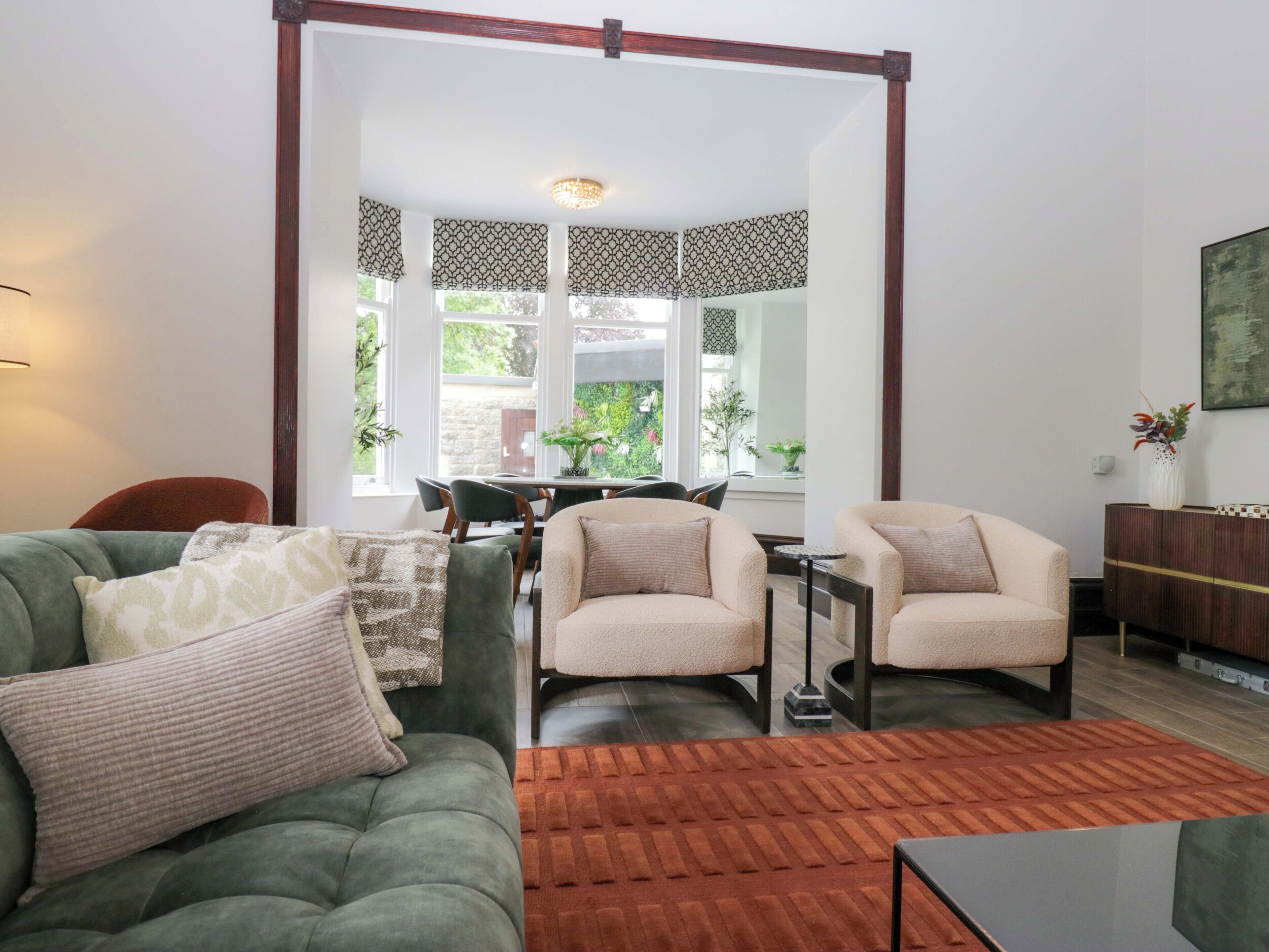 Una sala de estar con sofá, sillones, una mesa de centro y un comedor con sillas y una mesa.