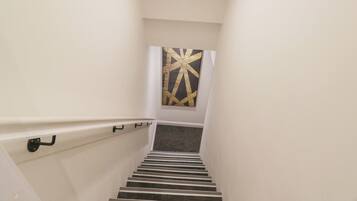 A staircase with a handrail, carpeted steps, and a wall-mounted artwork.