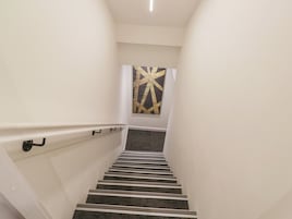 A staircase with a handrail, carpeted steps, and a wall-mounted artwork.