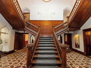 A grand staircase with a checkered floor leading to a landing with a sign reading 'Brettingham Holt Mansion.' - Brettargh Holt Mansion Sleeping 48 (Kendal)