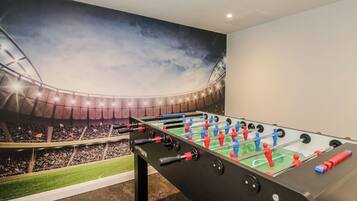 A foosball table in a room with a mural of a stadium.