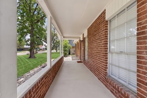 A covered corridor with brick walls and large windows.