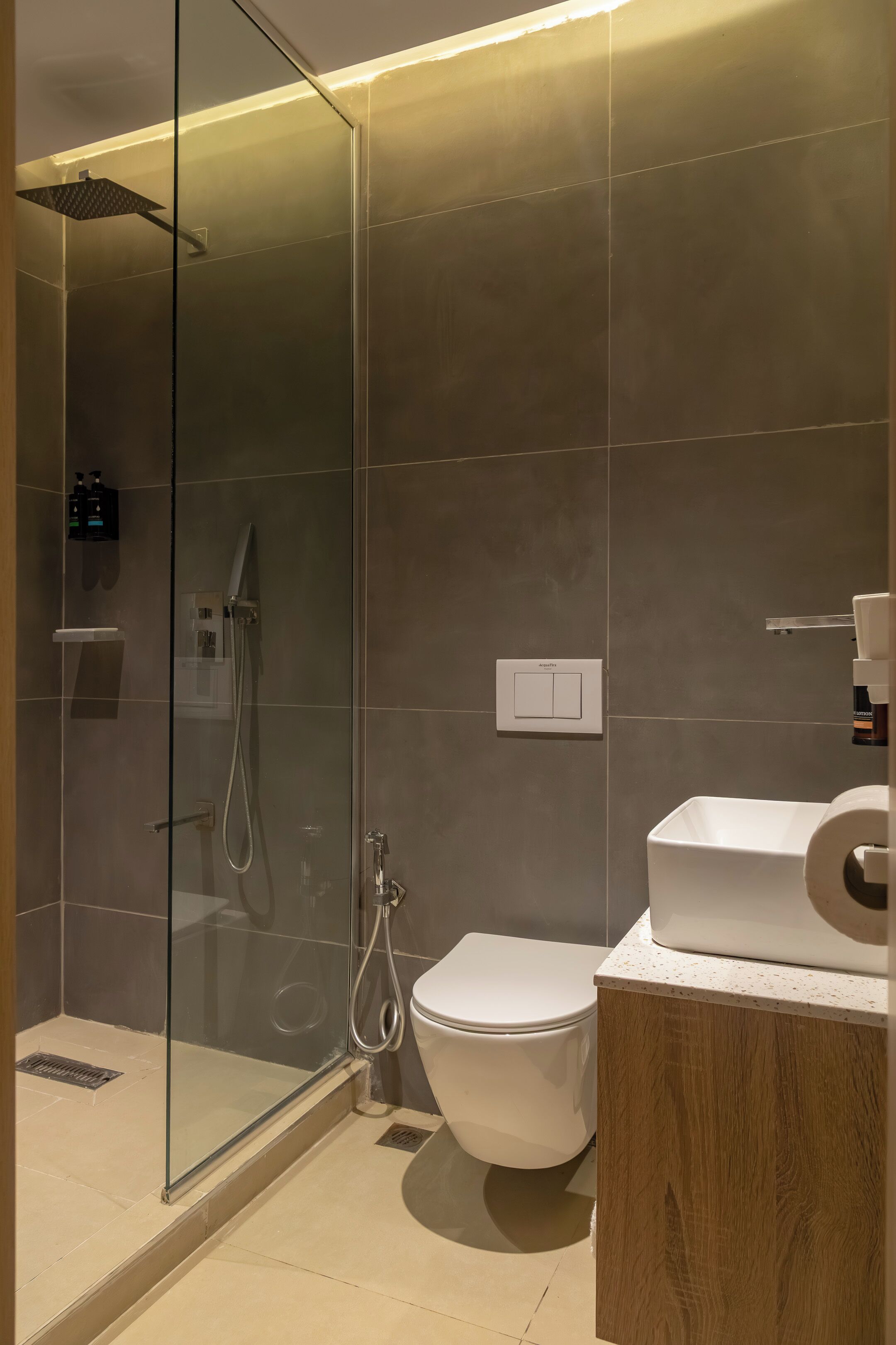 Ein modernes Badezimmer mit einer gläsernen Duschkabine, einer Toilette und einem hölzernen Waschtisch.
