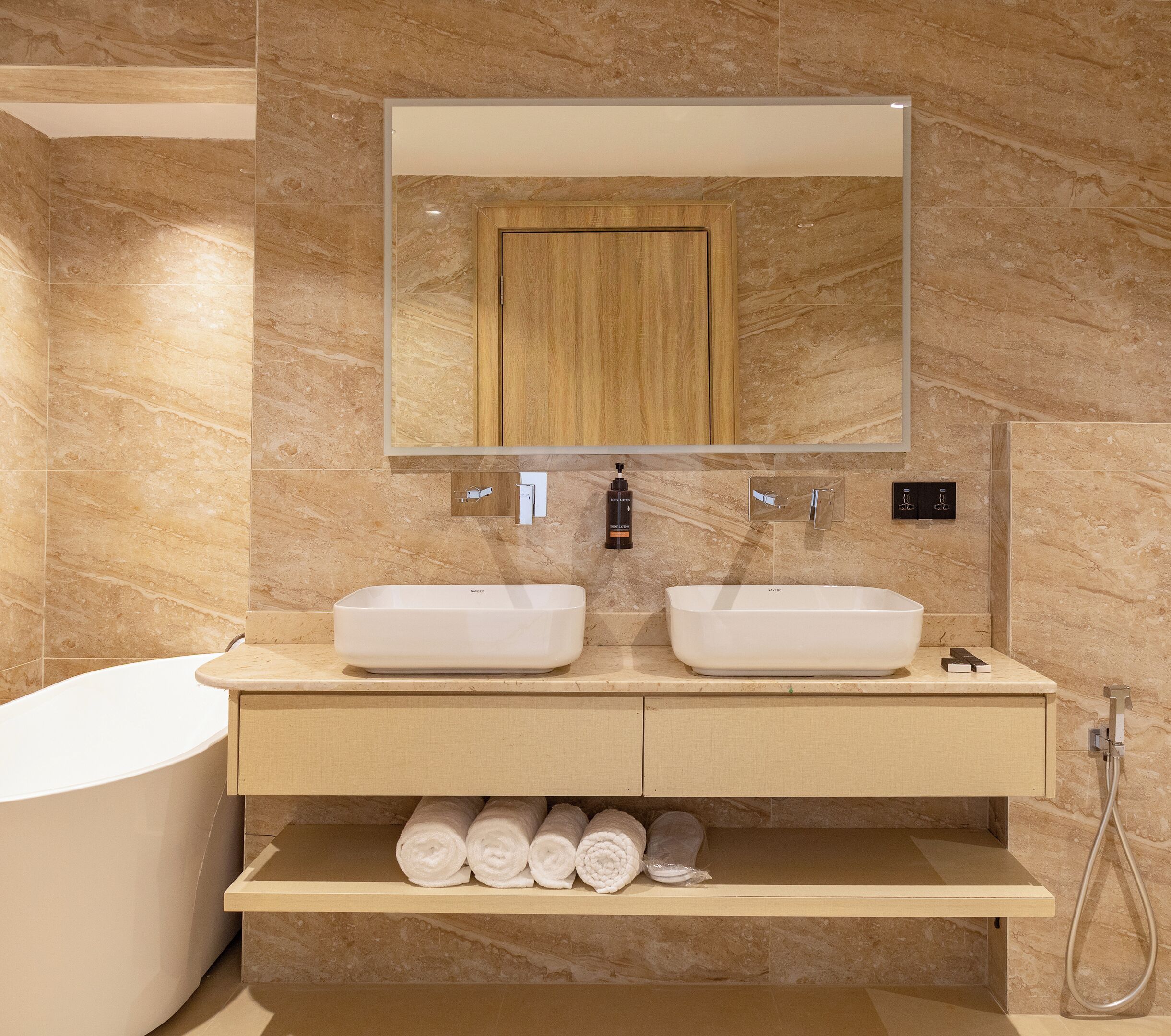 Une salle de bain moderne avec deux lavabos, un grand miroir, un meuble en bois et une baignoire.