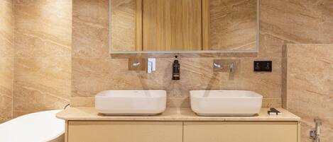 Une salle de bain moderne avec deux lavabos, un grand miroir, un meuble en bois et une baignoire.