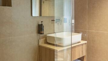 A modern bathroom with a glass shower enclosure, a wooden vanity, and a large mirror.