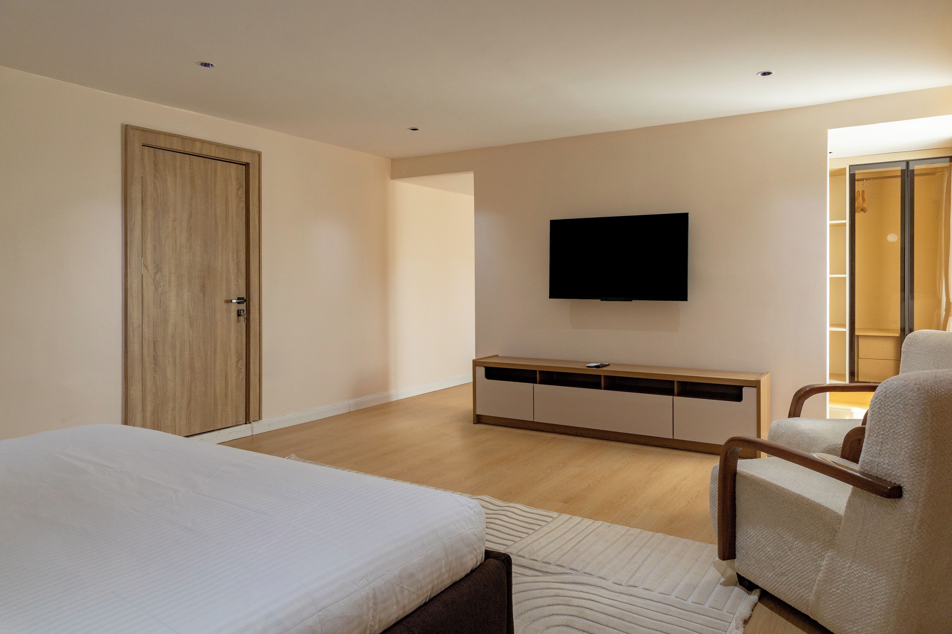 Un dormitorio con cama, televisor, armario y zona de estar.