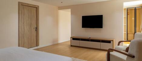 A bedroom with a bed, a TV, a wardrobe, and a seating area.