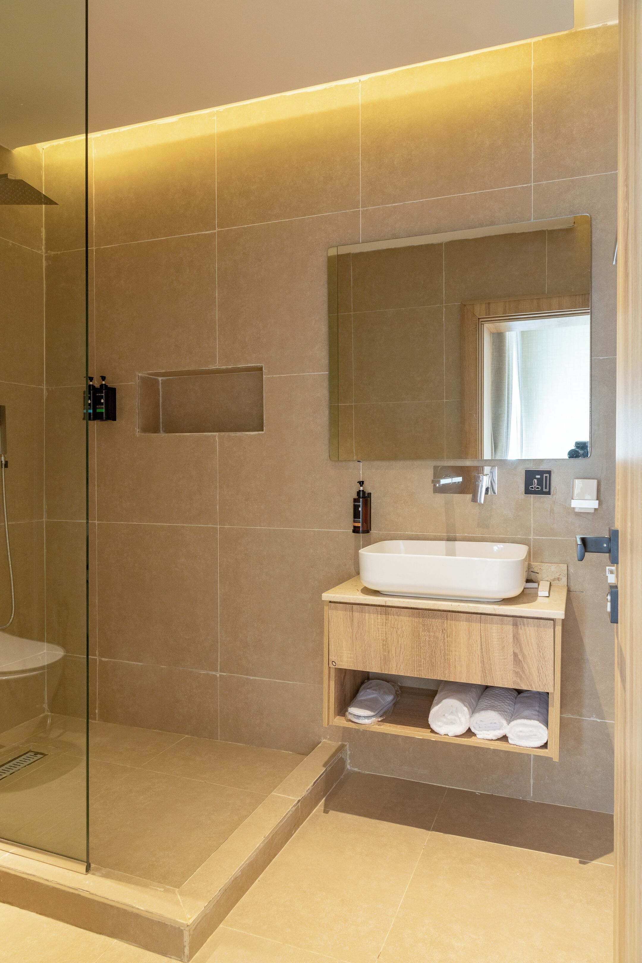 A modern bathroom with a glass shower enclosure, a large sink, and a mirror above it.