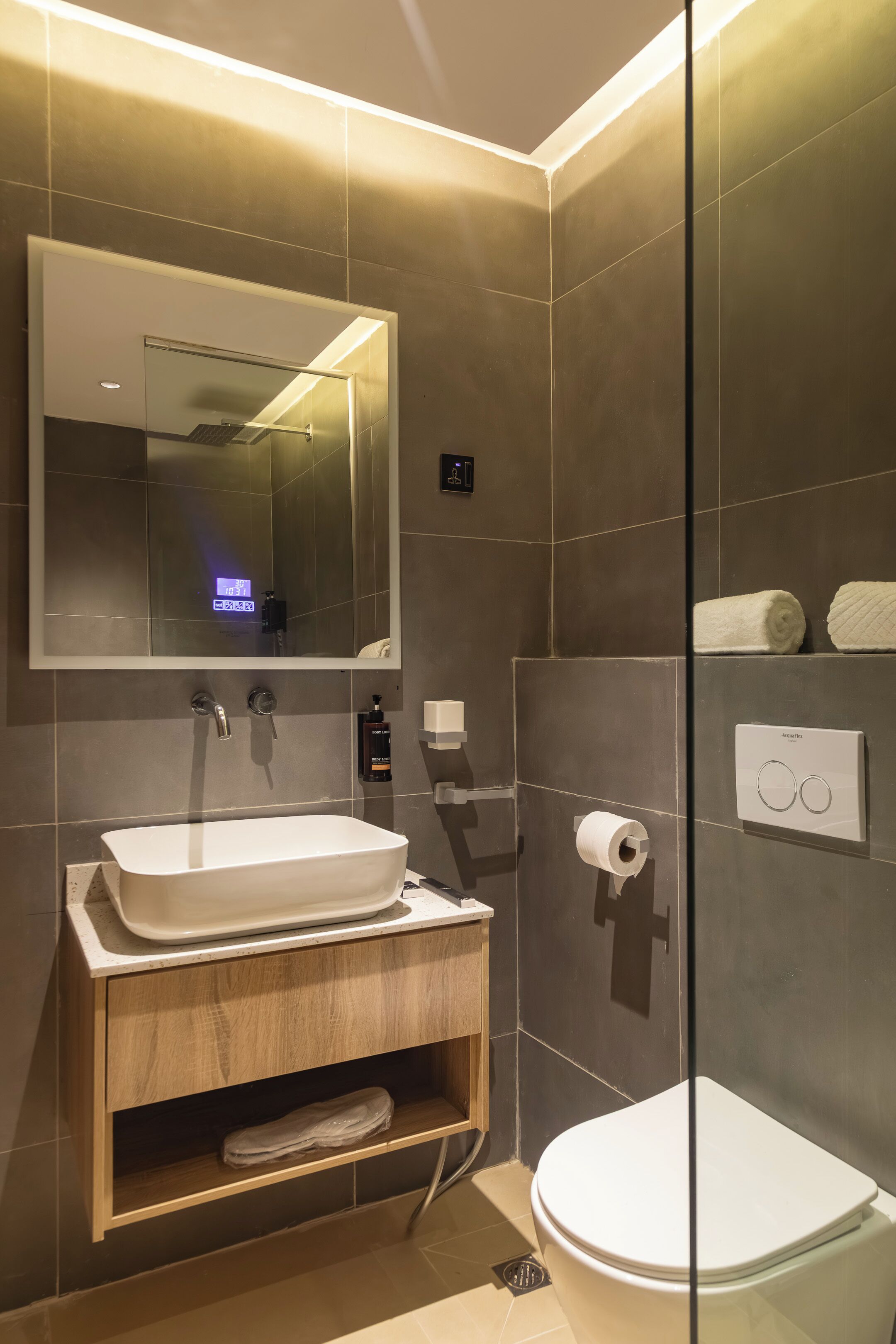 A modern bathroom with a large mirror, a sink, a toilet, and a glass shower enclosure.