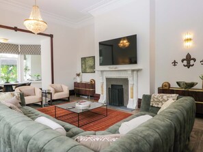 Una sala de estar con chimenea, televisor y comedor con mantel estampado.