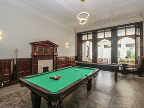 A billiards room with a pool table, a fireplace, and a view of the outside through large windows. - Brettargh Holt Mansion Sleeping 32 (Kendal)