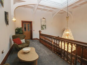 Eine Lobby mit einer Holztreppe, einem Chandelier und einer Tür mit satinierten Glasscheiben.
