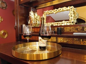 A bar area with two glasses of red wine on a tray, a bottle of wine, and a decorative mirror with a gold frame. - Brettargh Holt Mansion Sleeping 32 (Kendal)